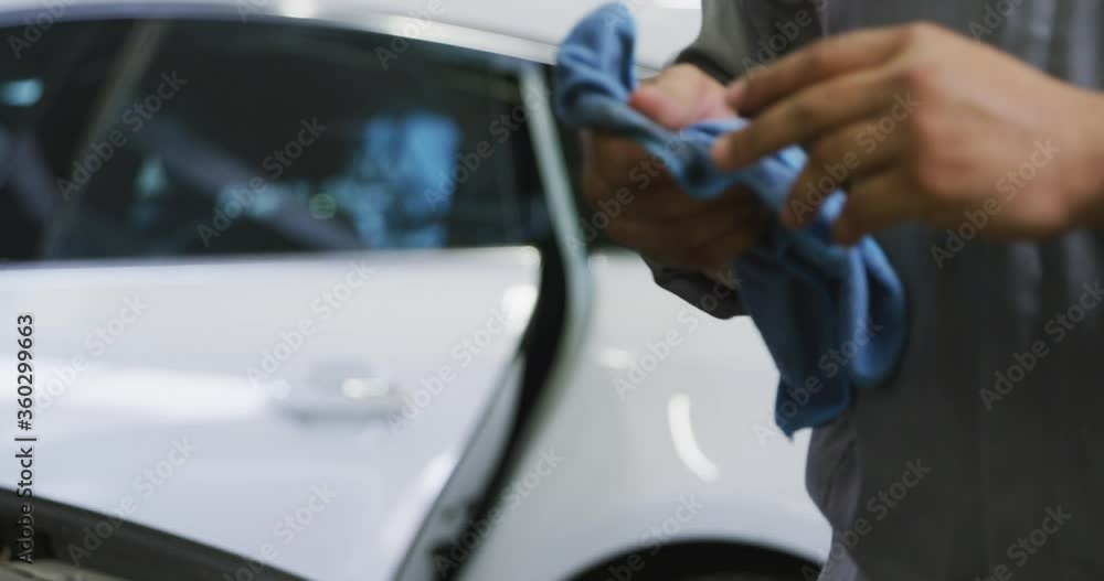 African American male car mechanic cleaning his hands with a rag African American male car mechanic cleaning his hands with a rag