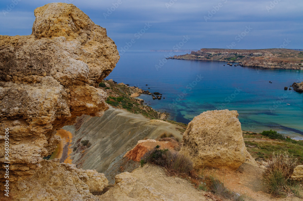 Incredible colors of view on colorful rocks on coastline in Malta. Juicy blue and green sea, blue sky. Beautiful landscapce. Hiking way on cliffs. Unforgettable scenery.