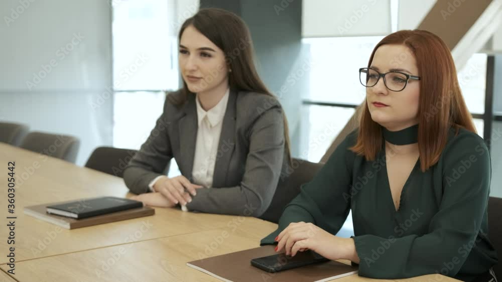 Businesswomen working in an office, view with two businesswomen sitting around a conference table with blank copy space. Business meeting concept Businesswomen working in an office, view with two businesswomen sitting around a conference table with blank copy space. Business meeting concept