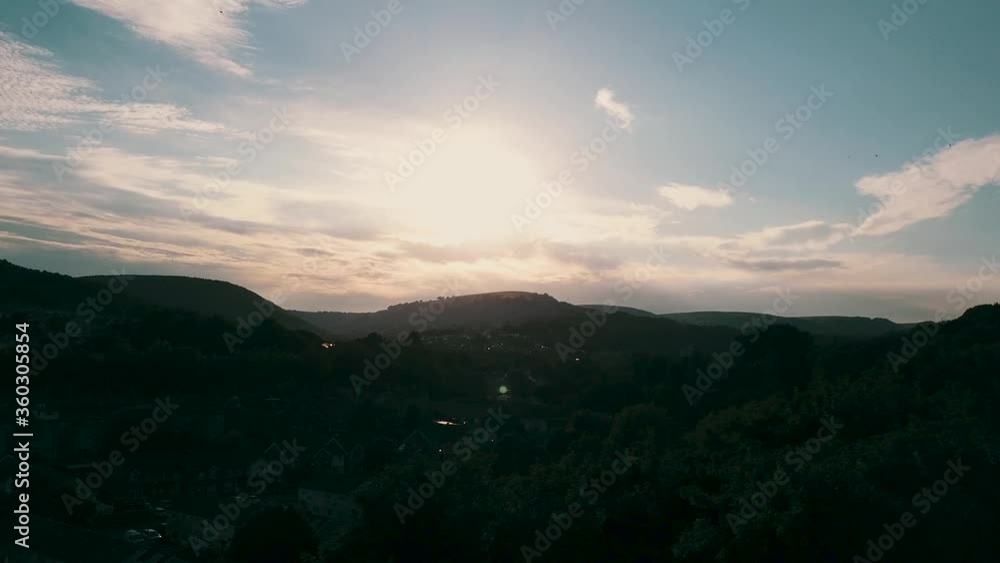 Slowly moving drone shot of a south wales town as sun sets behind mountains Slowly moving drone shot of a south wales town as sun sets behind mountains