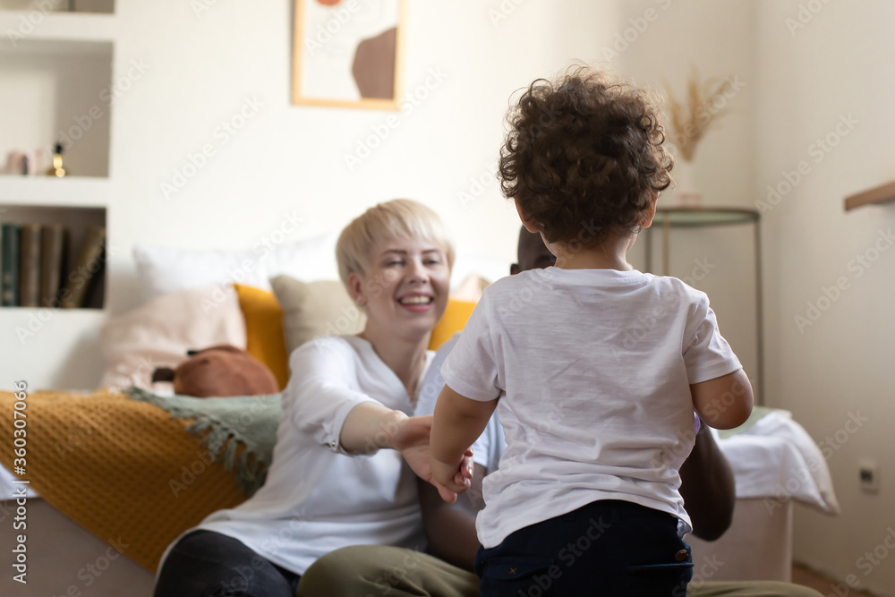 Fototapeta premium small child walks with his back to his happy parents