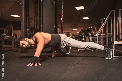 A bearded sporty man in the gym is doing Yoga exercises. Pungu Mayurasana – Wounded Peacock Posture photo