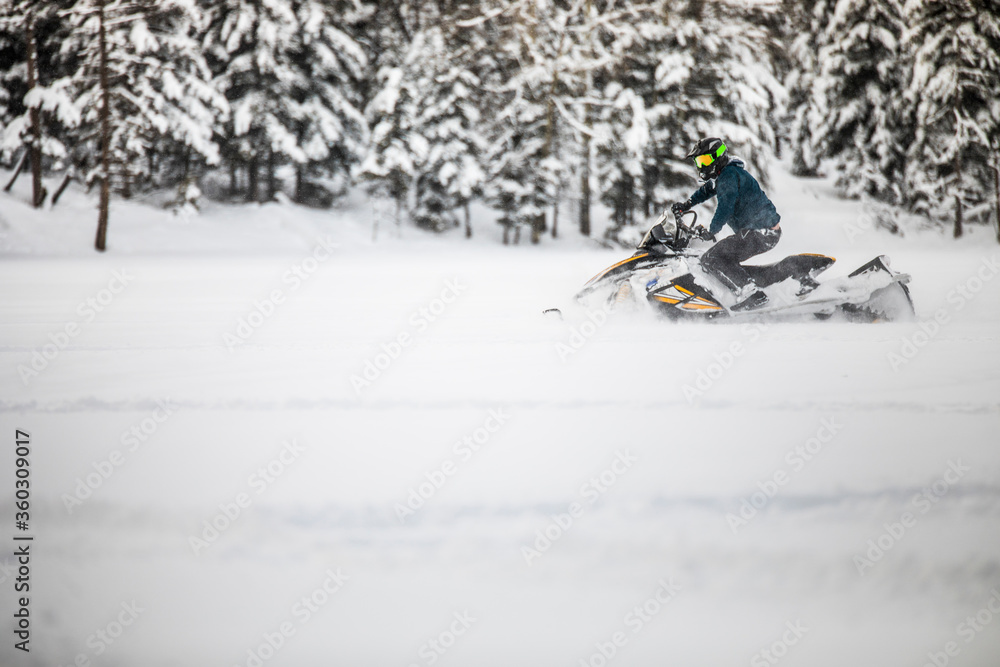 active man snowmobiling through deep snow during weekend getaway. active man snowmobiling through deep snow during weekend getaway.