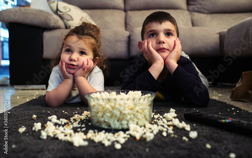 siblings watching a home movie while eating popcorn photo