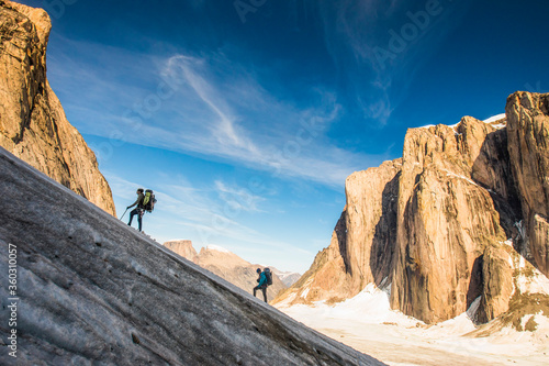 Backpackers hiking up glacier, ascending Mount Asgard, Baffin Island.