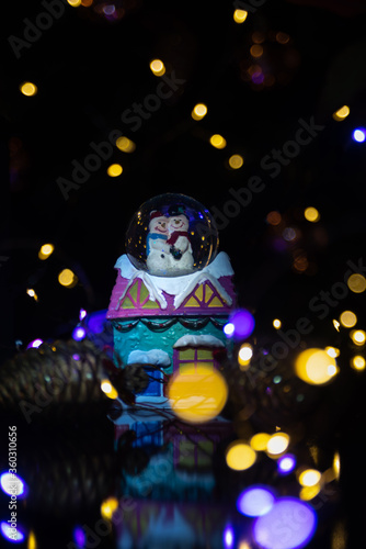 Christmas scene with tree, lights and snow globe. Selective focus on black background. © Milton Buzon