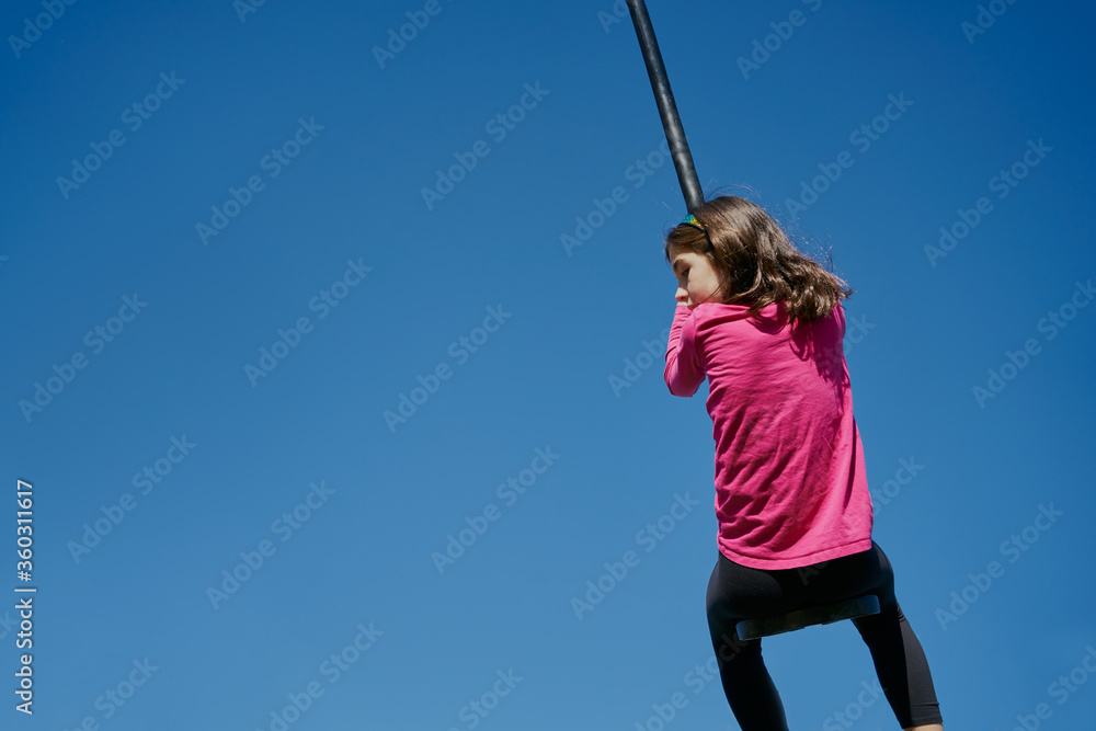 girl on a children's zip line with a blue sky background