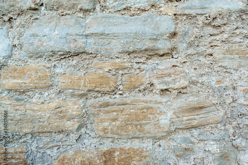 An old wall made of boulders or stones with cement or mortar is ideal for background and texture.