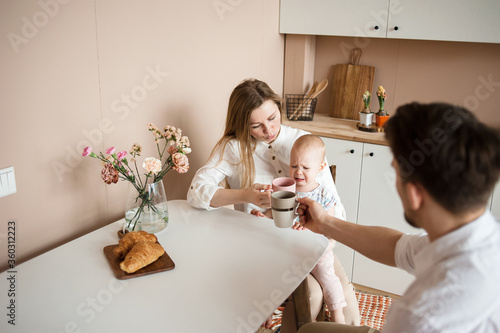 Parents comfort a crying child in the modern kitchen. Family routines photo