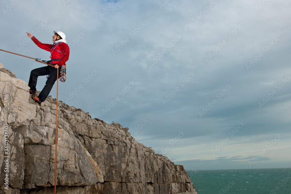 Female climber rappelling of seacliff in Swanage / England Female climber rappelling of seacliff in Swanage / England
