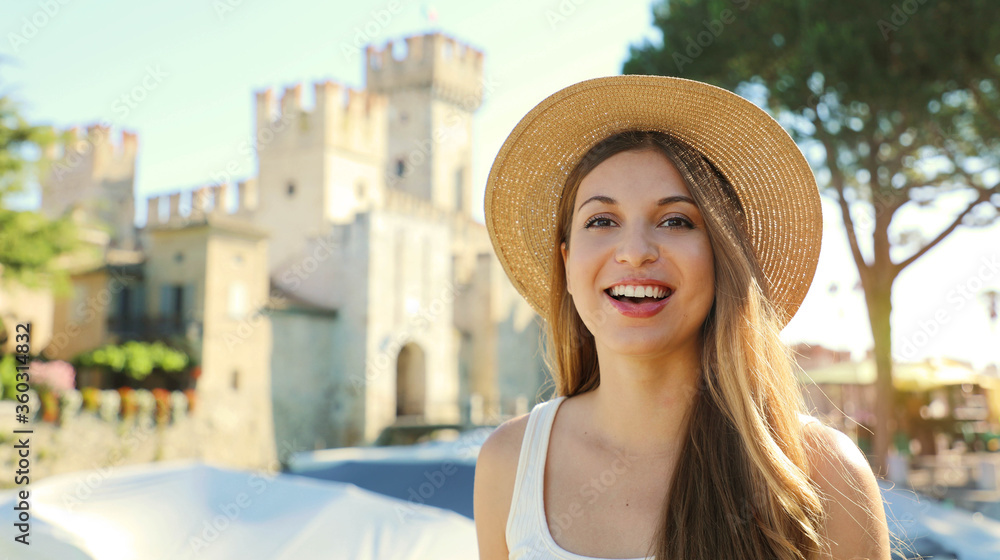 Portrait of smiling tourist woman with Sirmione Castle on the background, Lake Garda, Italy