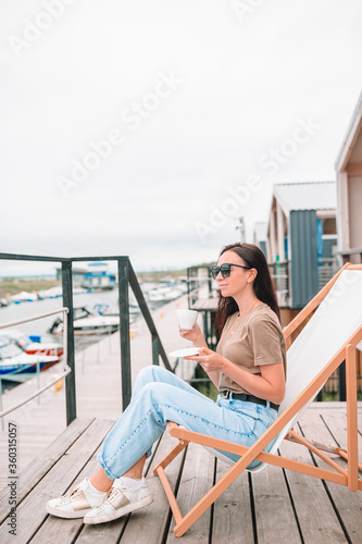 Young woman drinking hot coffee enjoying beach view.