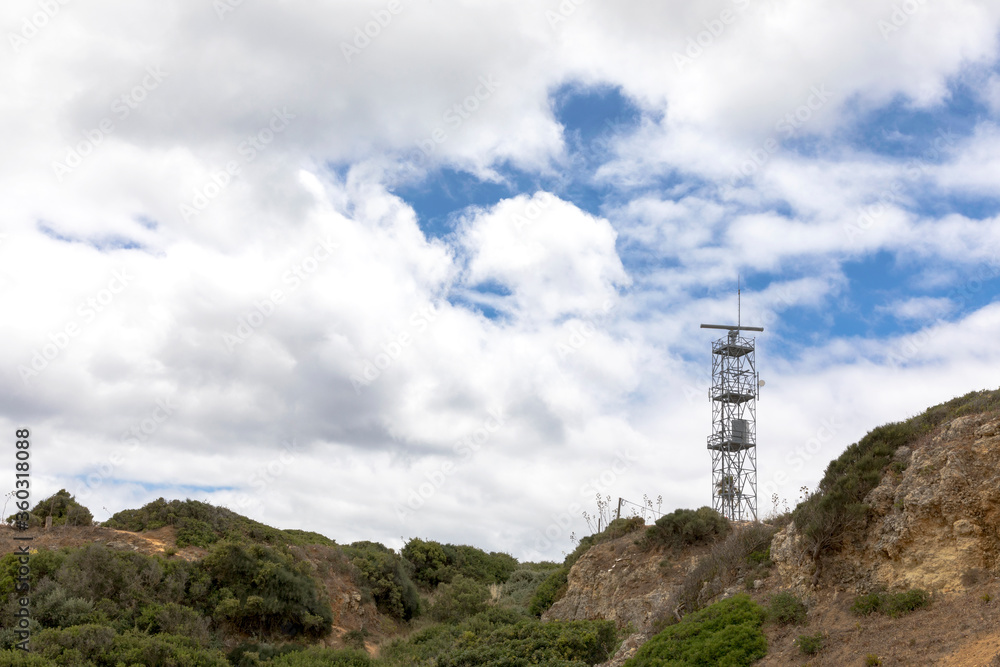 Natural landscape with port radar sonar installation for navigation in beach coast, against many white clouds and blue sky