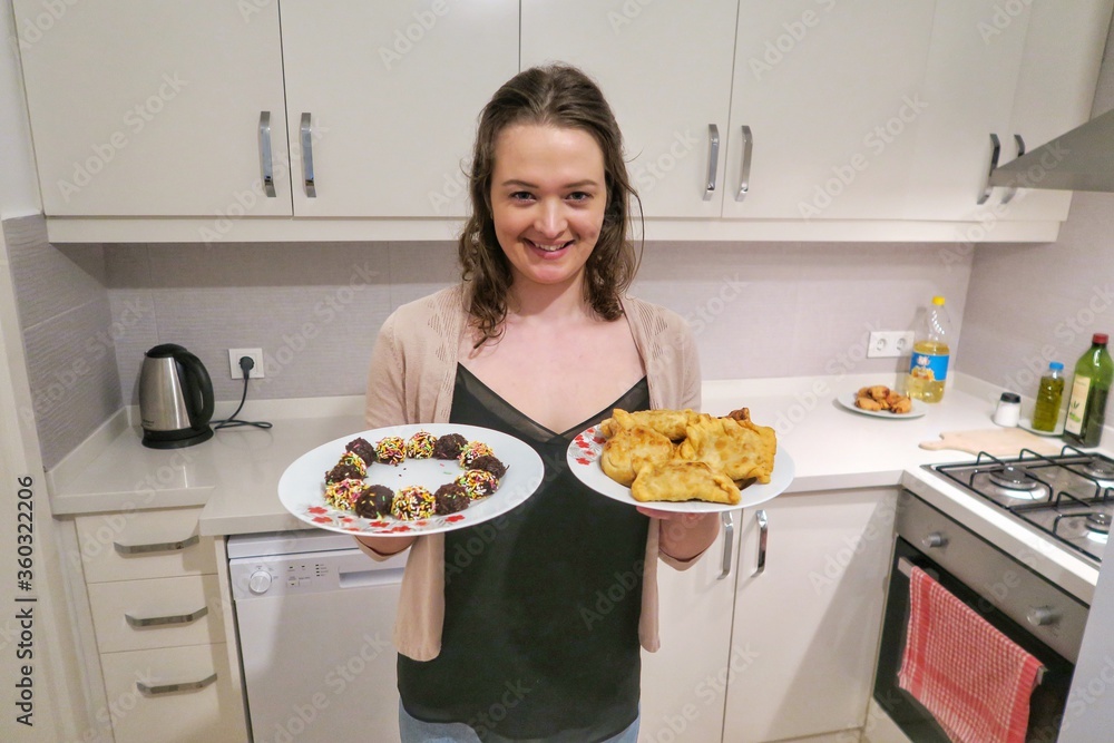 Young attractive woman cooking Brazilian food in the kitchen. White woman cooking Pastel and brigadeiros. Happy and proud of her cooking.