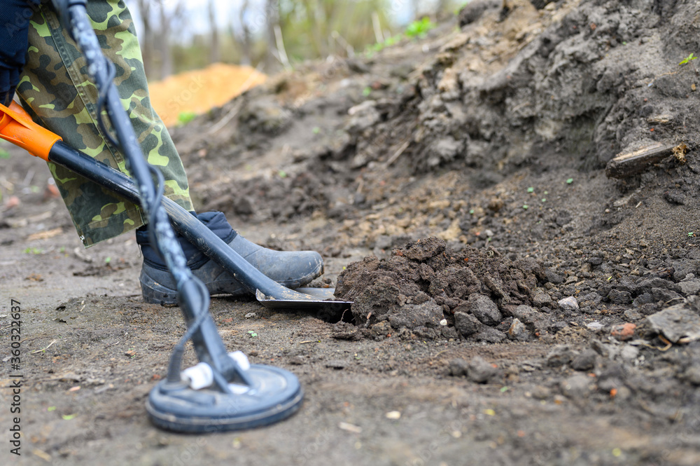 coil electronic metal detector device for search a treasure and the a man's foot is digging with a shovel coil electronic metal detector device for search a treasure and the a man's foot is digging with a shovel