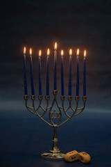 Burning blue candles on a Jewish menorah at Hanukkah with a dreidel on a dark blue background