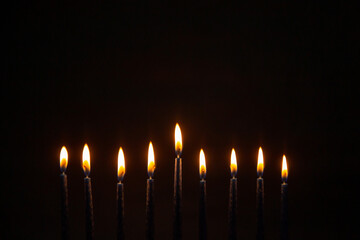Burning blue candles on a Jewish menorah at Hanukkah with a dreidel on a dark brown background
