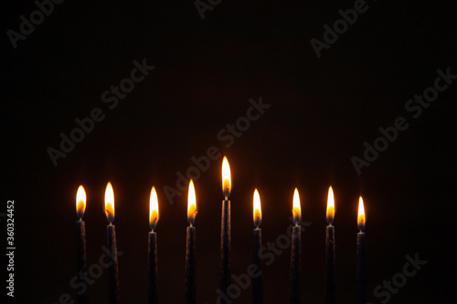 Burning blue candles on a Jewish menorah at Hanukkah with a dreidel on a dark brown background