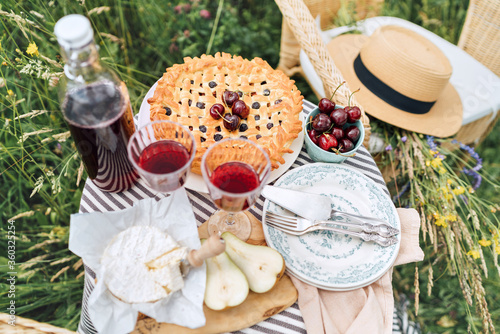 Table top view served with beautiful vintage wine glasses, silver cutlery, plates and tableware, tablecloth, sweet cherry pie and fresh cherries still life. Homemade baking and recipes illustration.