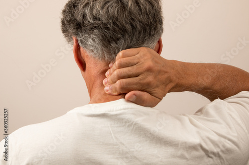 Senior Man with Headache massaging the back of his neck for relief