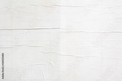 White crumpled paper poster with wavy creased surface texture background. White blank placard glued on billboard. Copy space for text.