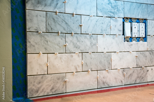 Marble subway tile backsplash installation showing tile spacers, before grout applied