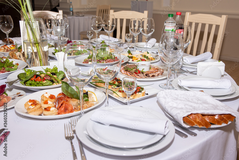 served and set table with dishes and utensils, white tones in the restaurant before the banquet