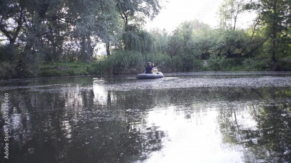 A handsome guy and a beautiful girl swim in a rubber boat on a lake in a fairy forest A handsome guy and a beautiful girl swim in a rubber boat on a lake in a fairy forest