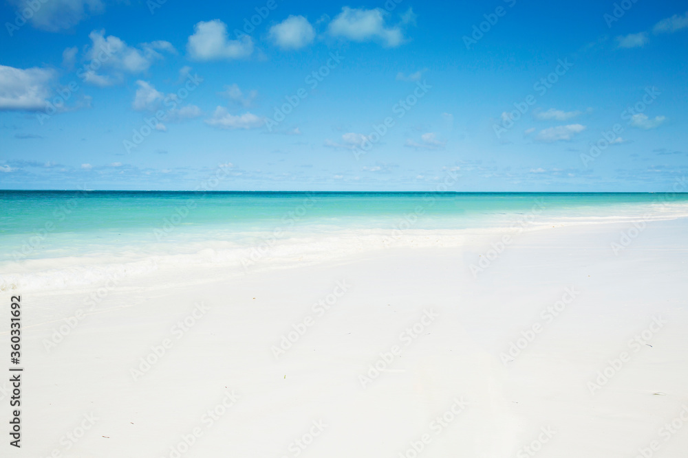 Clean white sand beach with turquoise water . Tropical island background. Small waves crushing on the beach.  Zanzibar island 