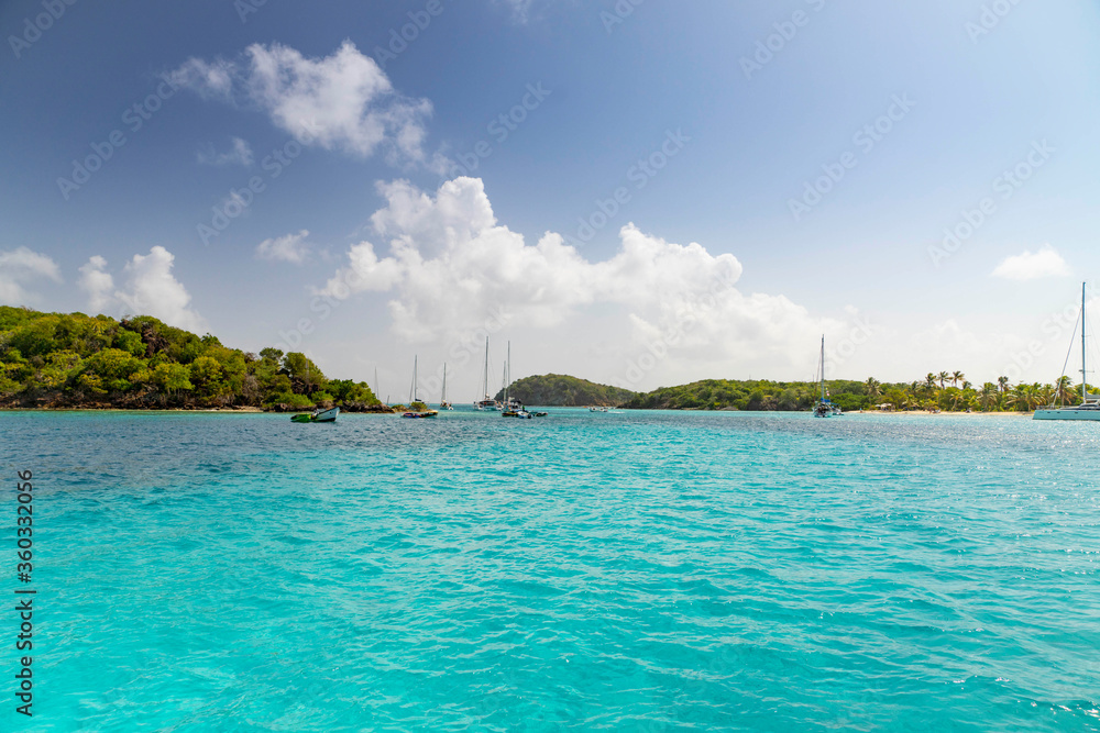  Seascape with turquoise blue water and sky with puffy clouds, sailboats and islands in the Caribbean Ocean