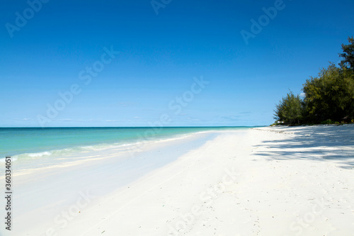 Clean white sand beach with turquoise water . Tropical island background. Small waves crushing on the beach. Clean empty white sand beach on Zanzibar. 