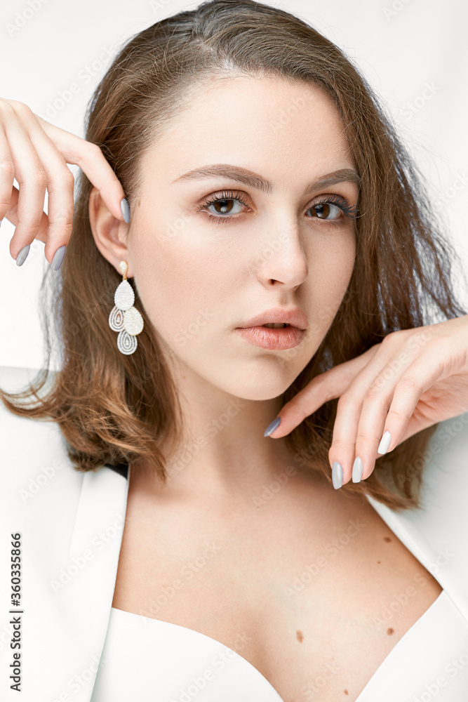 Fashionable portrait of a young beautiful girl with jewelry. Earrings with white crystals and diamonds.