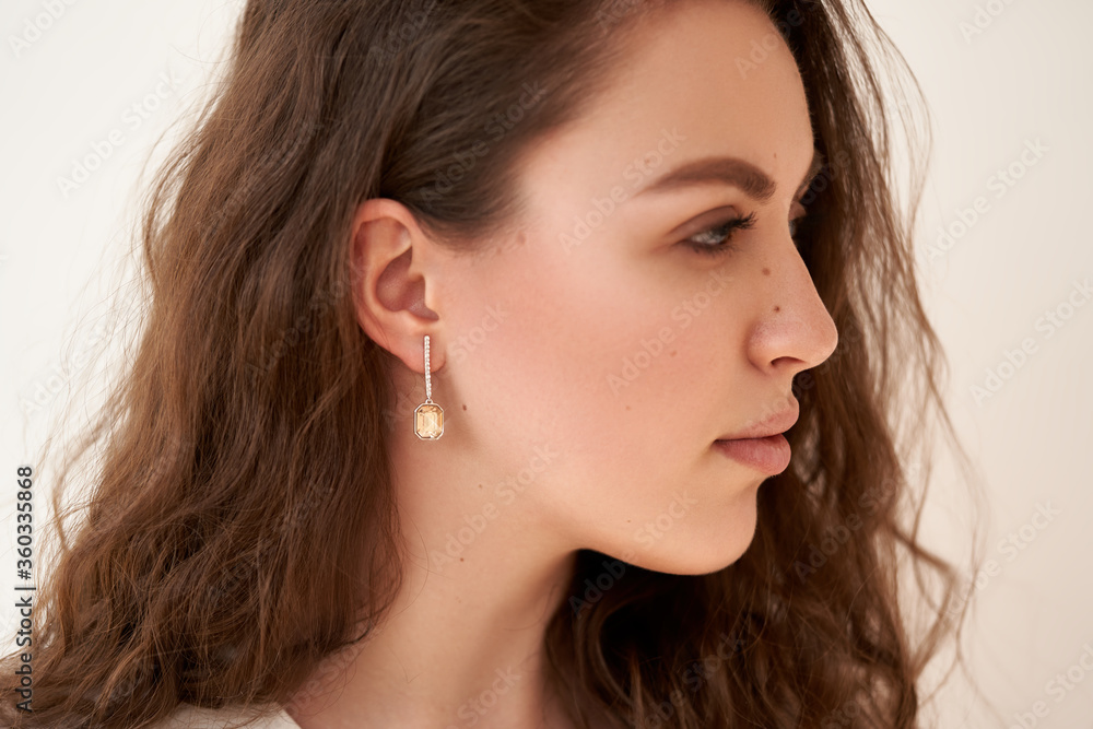Fashionable portrait of a young beautiful girl with jewelry. Earrings with white crystals and diamonds. Fashionable portrait of a young beautiful girl with jewelry. Earrings with white crystals and diamonds.