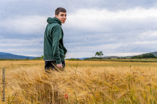 boy in sportswear in a wheat field strolls thoughtfully into the sunset © JuanFrancisco