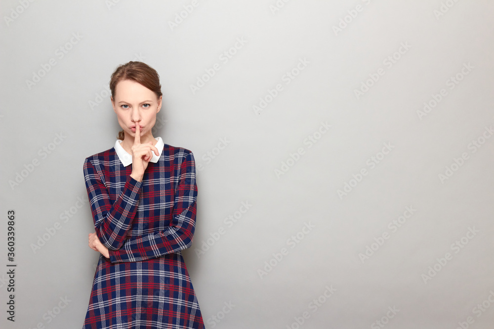 Portrait of strict girl showing silence gesture with finger over lips Portrait of strict girl showing silence gesture with finger over lips