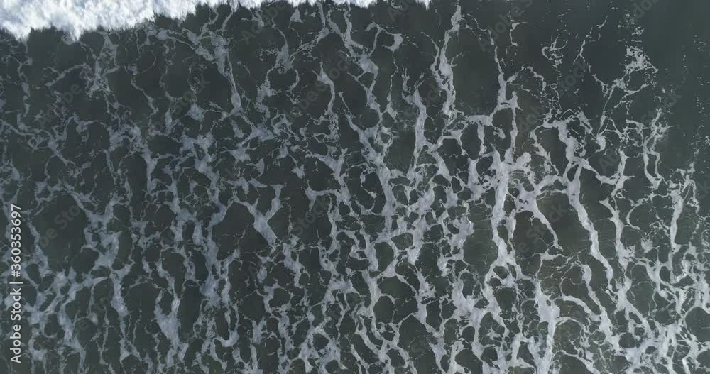 Aerial top down shot of foamy waves breaking on the shore Aerial top down shot of foamy waves breaking on the shore
