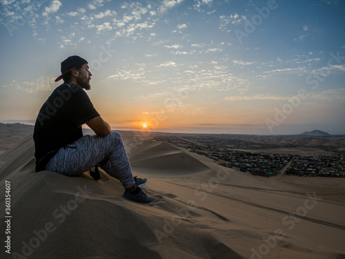 young man sitting in the top of a dune