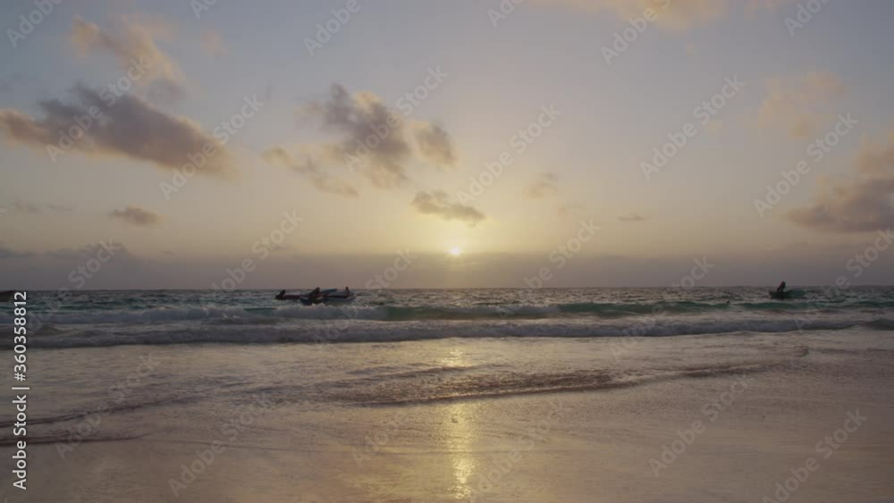 Some boats floating on the coast while the sun rises. Shot in slow motion in the beach of Tulum, Mexico Some boats floating on the coast while the sun rises. Shot in slow motion in the beach of Tulum, Mexico