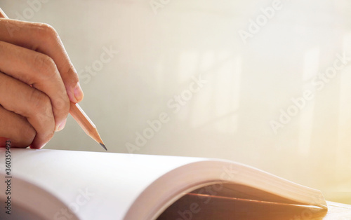 Woman hand writing with pencil on notebook