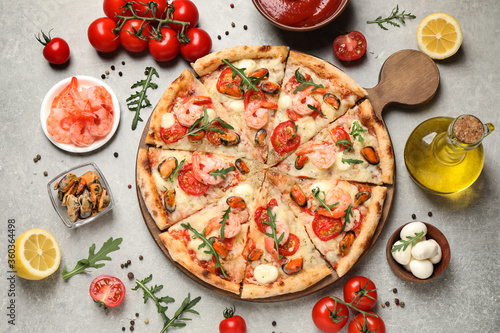 Delicious seafood pizza and fresh ingredients on light grey table, flat lay