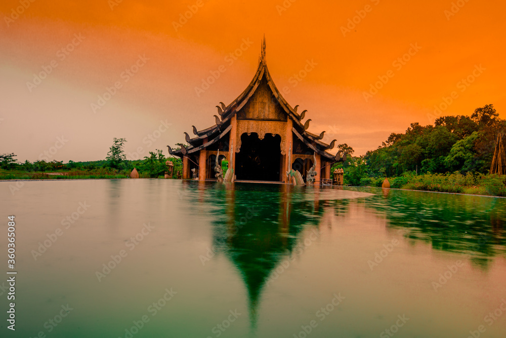 The background of the Wat Pa Kham Charoen is a beautiful old church with a Buddhist statue and a tree-lined temple, with tourists and travelers always making merit in Udon Thani, Thailand.