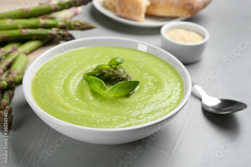 Delicious asparagus soup served on grey table, closeup
