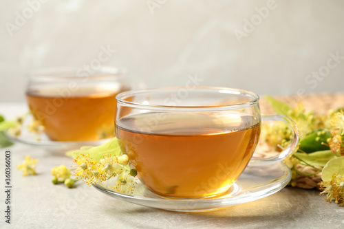 Tasty tea and linden blossom on light grey table
