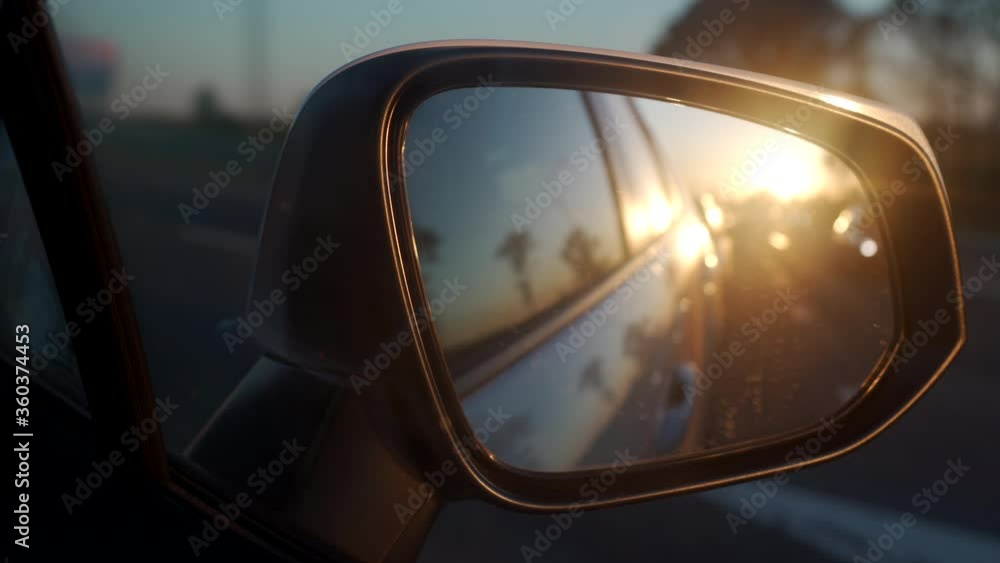 Driving car at sunset sun rays and cars reflected in side rearview mirror automobile on highway closeup. Driving car at sunset sun rays and cars reflected in side rearview mirror automobile on highway closeup.