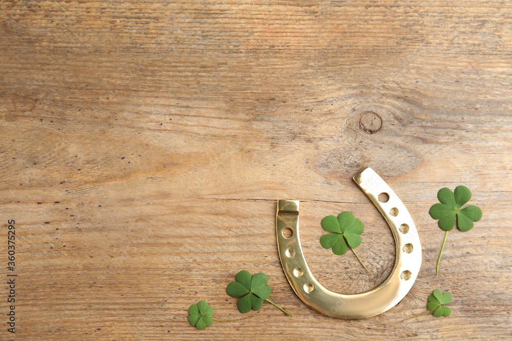 Clover leaves and horseshoe on wooden table, flat lay with space for text. St. Patrick's Day celebration Clover leaves and horseshoe on wooden table, flat lay with space for text. St. Patrick's Day celebration