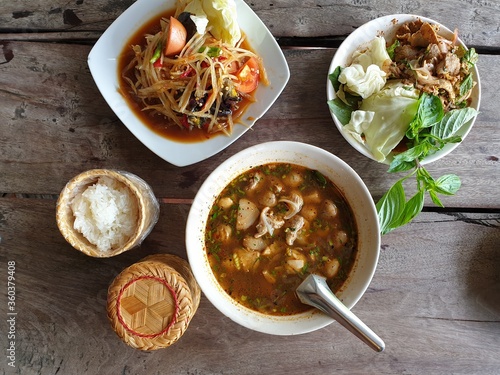 som tum Thai with sticky rice and hot and spicy soup on wooden table