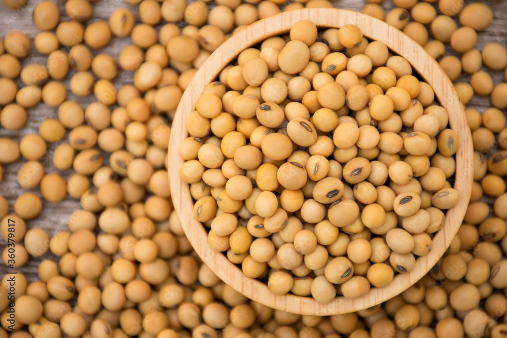 Closeup soy beans in wooden bowl isolated on wood table background. Overhead view. Flat lay. Closeup soy beans in wooden bowl isolated on wood table background. Overhead view. Flat lay.