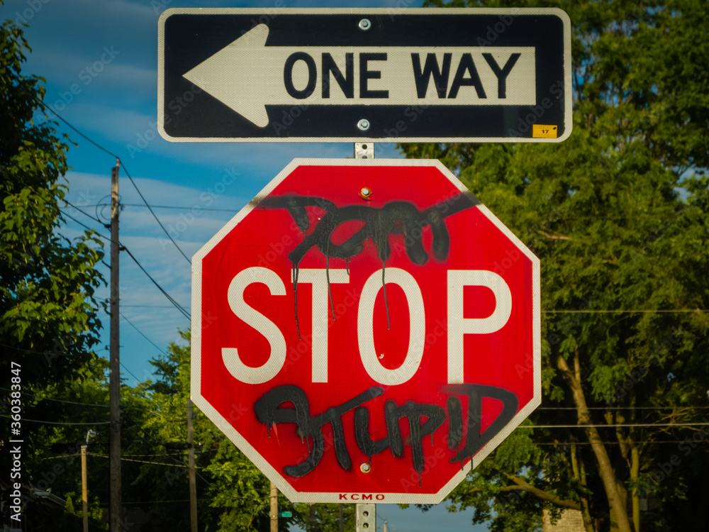 Defaced stop sign with one-way sign above it