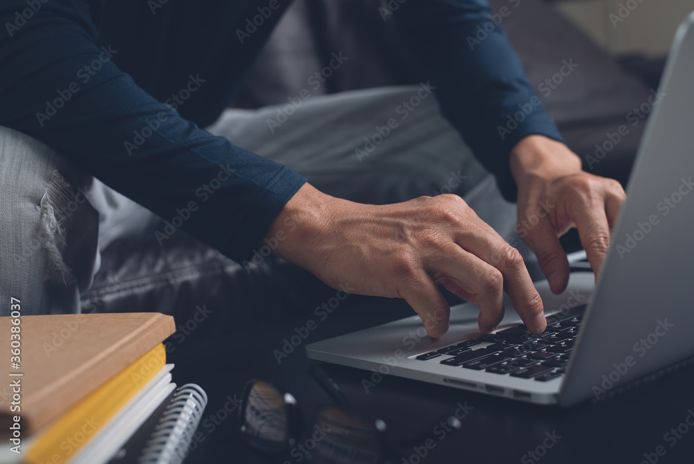 Casual business man surfing the internet online working on laptop at home