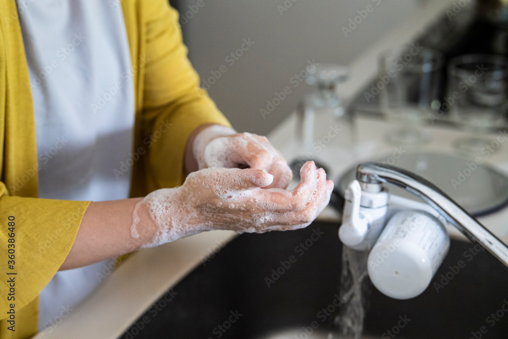 丁寧にキッチンで手洗いをする女性